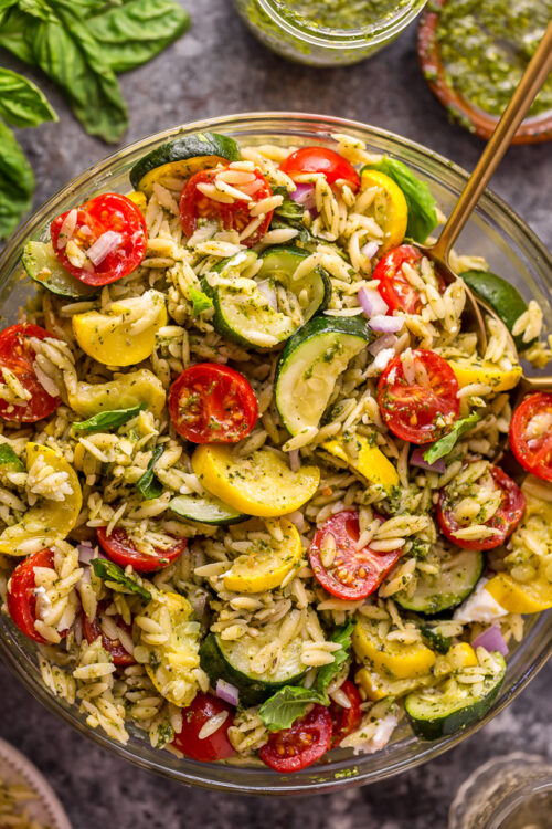 It's beginning to feel a lot like Summer, and you know what that means, right? It's PASTA SALAD SEASON! And this Pesto Orzo Pasta Salad with Zucchini, Goat Cheese, and Tomatoes is sure to be on heavy rotation all Summer long! This mayo-free pasta salad is vegetarian friendly and perfect for picnics, potlucks, and barbecues! #pestopastasalad #pesto #orzo #orzopastasalad